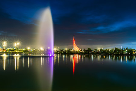 UZBEKISTAN, TASHKENT - SEPTEMBER 15, 2023: Illuminated monument of independence in the form of a stele with a Humo bird and fountain in the New Uzbekistan park at nighttime in autumn evening.のeditorial素材