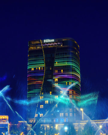 Uzbekistan, Tashkent - September 27, 2023: A fountain with laser illumination and light music in Tashkent City Park at nighttime against the backdrop of the Hilton Hotel.のeditorial素材