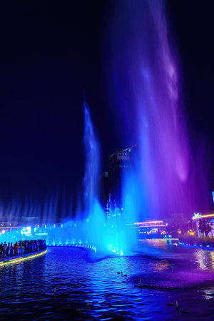 Uzbekistan, Tashkent - September 27, 2023: A fountain with laser illumination and light music in Tashkent City Park at nighttime against the backdrop of a scyscrapers.のeditorial素材
