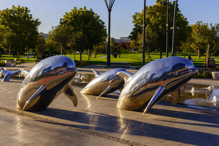 Uzbekistan, Tashkent - September 27, 2023: A fountain with shiny steel dolphins in Tashkent City Park at sunset.のeditorial素材