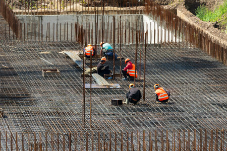 Russia, Kaluga - August 20, 2022: A group of workers assembling the framework of a building from...