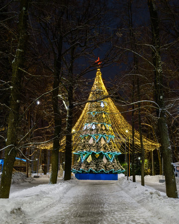 Artificial Christmas tree in garlands at night park. Xmas decorations and lights.の写真素材