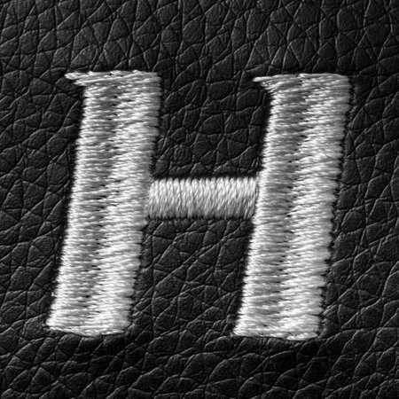Letter H embroidered with white threads on black leather background. English alphabet. Element for design.の写真素材