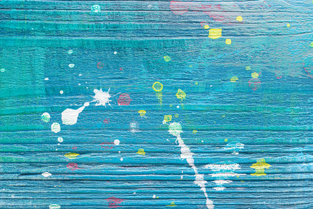 Blue painted textured wooden plank with colorful paint stains. Abstract background for design.の写真素材