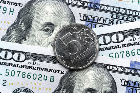 Close-up of a 5 Russian rubles coin placed on US 100 dollar bills, on a white background. Concept of currency comparison and exchangeの写真素材
