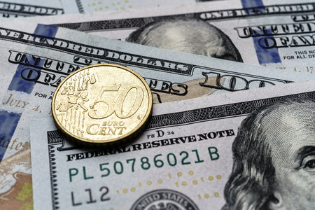 Close-up of a 50 euro cent coin placed on US 100 dollar bills, on a white background. Concept of currency comparison and exchangeの写真素材