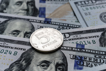 Close-up of a 5 Russian rubles coin placed on US 100 dollar bills, on a white background. Concept of currency comparison and exchangeの写真素材