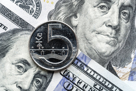 Close-up of a Czech crown coin placed on US 100 dollar bills, on a white background. Concept of currency comparison and exchange.の写真素材