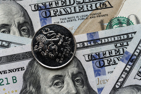 Close-up of a Czech crown coin placed on US 100 dollar bills, on a white background. Concept of currency comparison and exchange.の写真素材