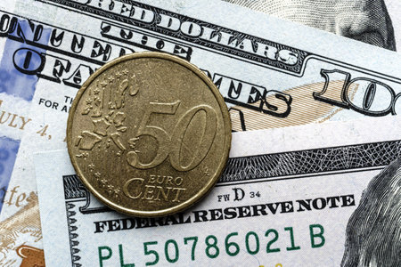 Close-up of a 50 euro cent coin placed on US 100 dollar bills, on a white background. Concept of currency comparison and exchangeの写真素材