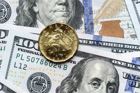 Close-up of a Czech crown coin placed on US 100 dollar bills, on a white background. Concept of currency comparison and exchangeの写真素材