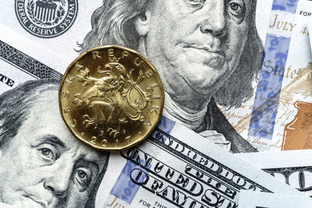 Close-up of a Czech crown coin placed on US 100 dollar bills, on a white background. Concept of currency comparison and exchangeの写真素材