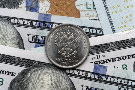 Close-up of a Russian rubles coin placed on US 100 dollar bills, on a white background. Concept of currency comparison and exchangeの写真素材