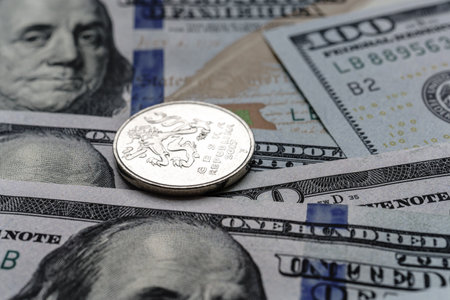 Close-up of a Czech crown coin placed on US 100 dollar bills, on a white background. Concept of currency comparison and exchange.の写真素材