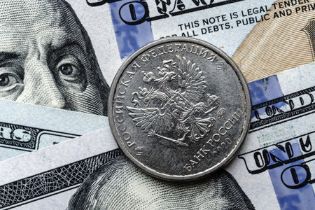 Close-up of a Russian rubles coin placed on US 100 dollar bills, on a white background. Concept of currency comparison and exchangeの写真素材