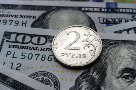 Close-up of a 2 Russian rubles coin placed on US 100 dollar bills, on a white background. Concept of currency comparison and exchangeの写真素材