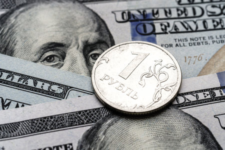 Close-up of a 1 Russian rubles coin placed on US 100 dollar bills, on a white background. Concept of currency comparison and exchangeの写真素材
