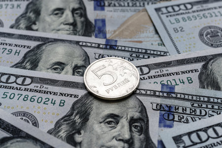 Close-up of a 5 Russian rubles coin placed on US 100 dollar bills, on a white background. Concept of currency comparison and exchangeの写真素材
