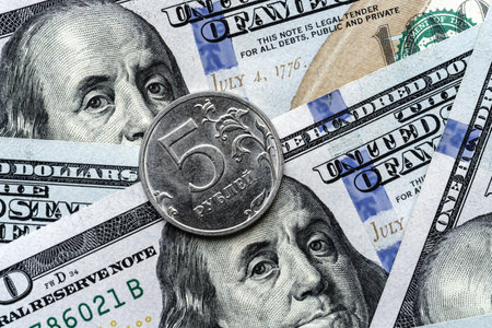 Close-up of a 5 Russian rubles coin placed on US 100 dollar bills, on a white background. Concept of...