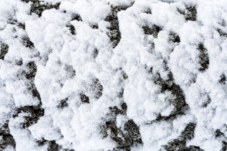Snow-covered textured surface with intricate details, natural tones, and bright white background, highlighting winter nature.の写真素材