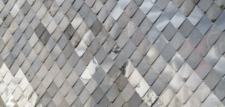 Close-up of gray metal roof panels with detailed texture and light reflections, forming a geometric...