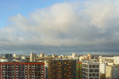 Urban residential complex with vibrant facades in a cityscape, sunny weather, and cloudy sky, concept of modern city architecture.の写真素材
