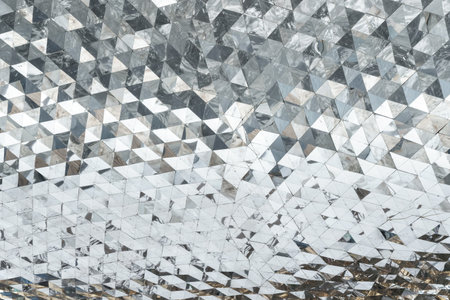 Close-up of gray metal roof panels with detailed texture and light reflections, forming a geometric...