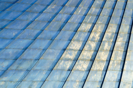 Close-up of blue metal roof panels with detailed texture and light reflections, forming a geometric pattern, architectural concept. Abstract background.の写真素材