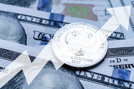 Close-up of a Russian ruble coin placed on US 100 dollar bills and arrow up. Concept of currency increase.の写真素材