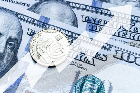 Close-up of a Israel shekel coin placed on US 100 dollar billsand arrow up. Concept of currency increasing.の写真素材