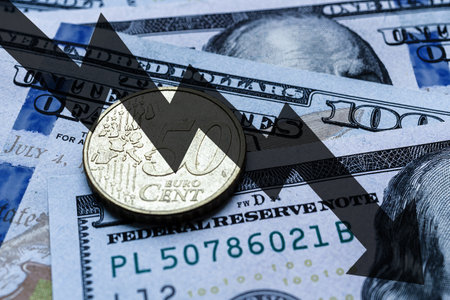 Close-up of a 50 euro cent coin placed on US 100 dollar bills and arrow down. Concept of currency falling.の写真素材