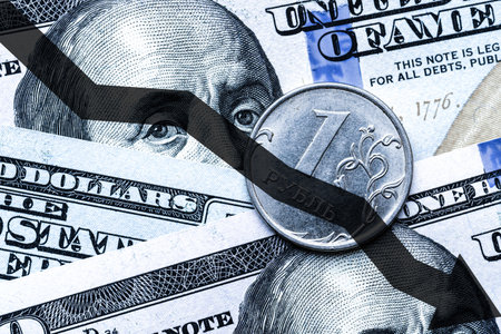 Close-up of a Russian ruble coin placed on US 100 dollar bills and arrow down. Concept of currency falling.の写真素材