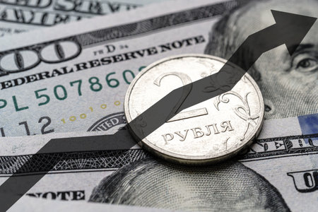 Close-up of a Russian ruble coin placed on US 100 dollar bills and arrow up. Concept of currency increase.の写真素材
