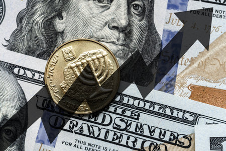 Close-up of a Israel shekel coin placed on US 100 dollar bills and arrow up. Concept of currency increase.の写真素材