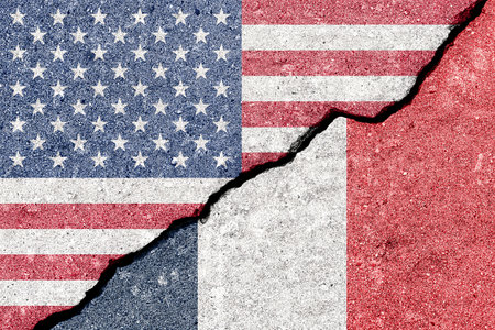 Franco o American tension and conflict. A geopolitical crack, split shows US and France flags on wall. Concept of representing diplomacy challenges for international relations. World affairs.の写真素材