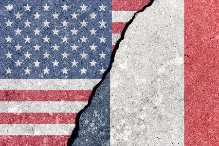 Franco o American tension and conflict. A geopolitical crack, split shows US and France flags on wall. Concept of representing diplomacy challenges for international relations. World affairs.の写真素材