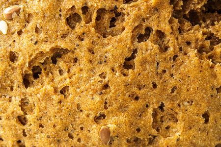 Close detailed macro view of wholesome brown whole grain bread texture showing the porous crust of...