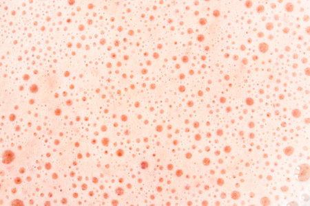 Pink foam texture with small bubbles on a light pink background. Close up macro view of a liquid surface with air bubbles. Smooth beverage background abstract concept.の写真素材
