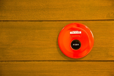 red fire alarm bell set against wood wallの写真素材