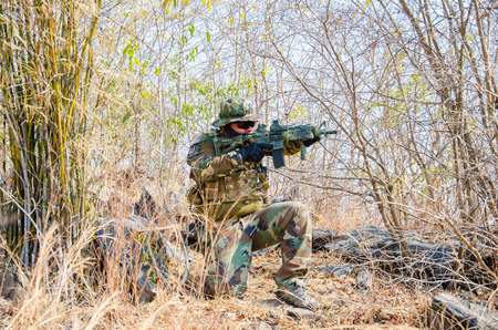 SUPANBURI - FEBRUARY 7 : Airsoft team member in during action hiding in the bushes to protect the...