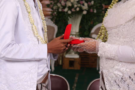 bridal hands and red velvet box with a pair of gold wedding rings