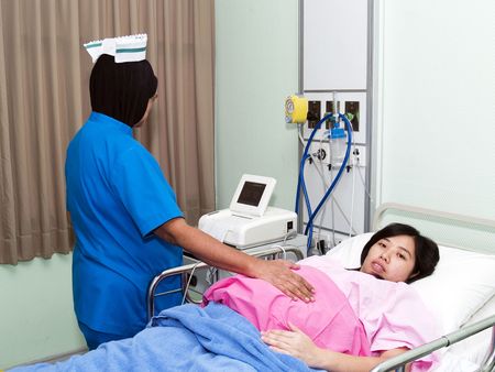 Nurse checking pregnant women tummy at hospitalの写真素材