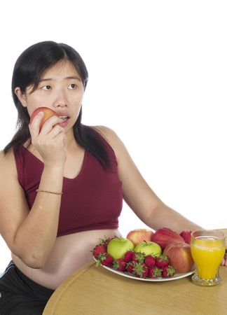 A pregnant women eat her apple with white backgroundの写真素材