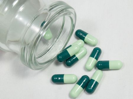 Green medicine pour out from bottle on white backgroung