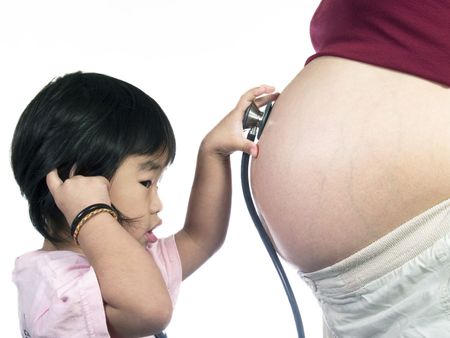 Asian kid listen her mother tummy with stethoscopeの写真素材