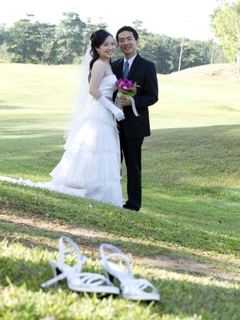Wedding couple holding flower bouquet smiling in the golf courseの写真素材