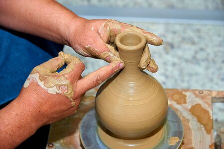 Hands of a potter. Potter making ceramic vase on the pottery wheel.の写真素材