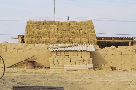 Landscape of the Kazakh village. Haystack, a pile of clay bricks at the clay wallの写真素材