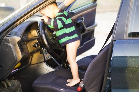 Little boy is playing at the wheel of a carの写真素材