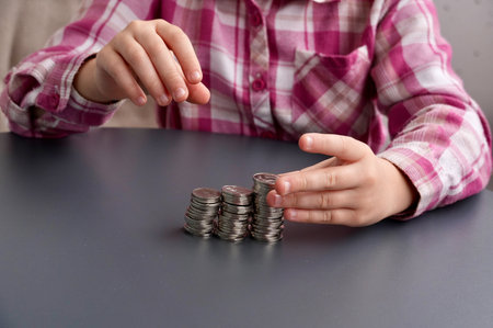 Little girl counting coins on table, closeup. Money savings concept